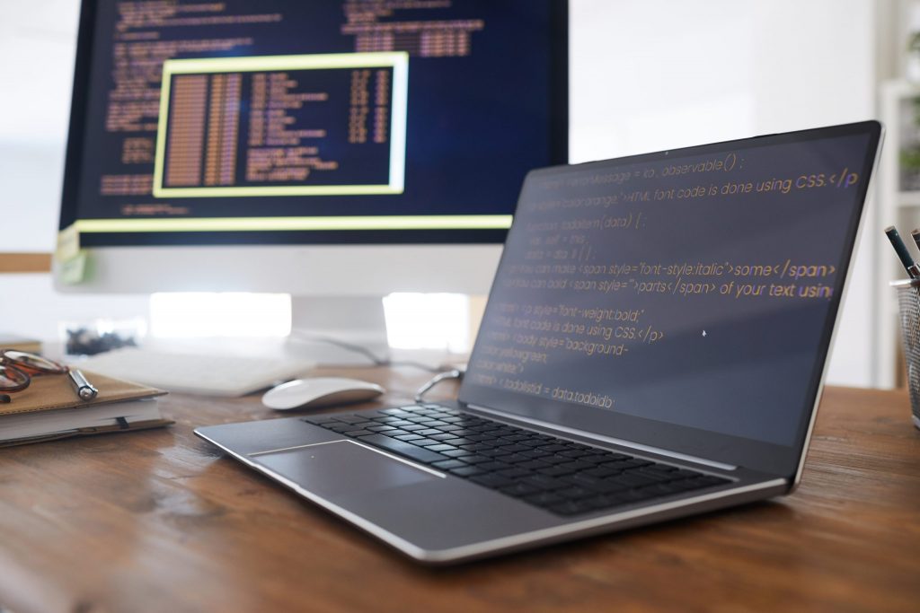Laptop and desktop displaying code, symbolising Mocean SMS API integration for developers in Indonesia.